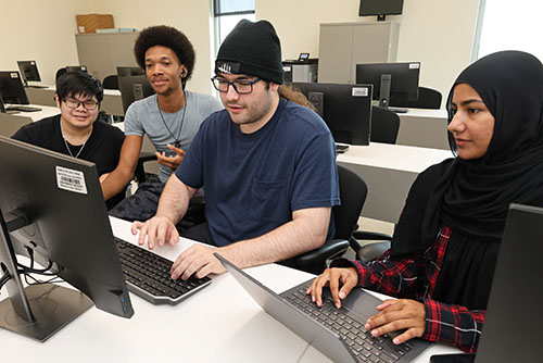 Four college students on computers collaborating on project