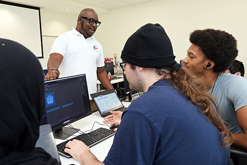 Game design teacher working with students at computer